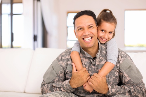 A smiling military member and his child